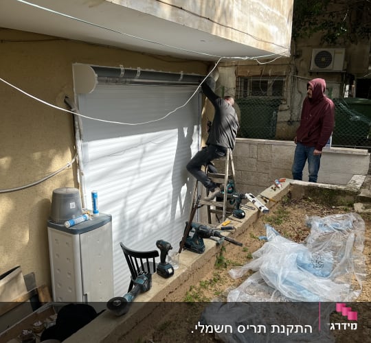 עובד מתקין תריס אלומיניום עם כלים חשמליים